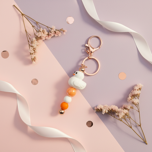 White duck charm beaded keychain lifestyle flat lay on pink and purple background